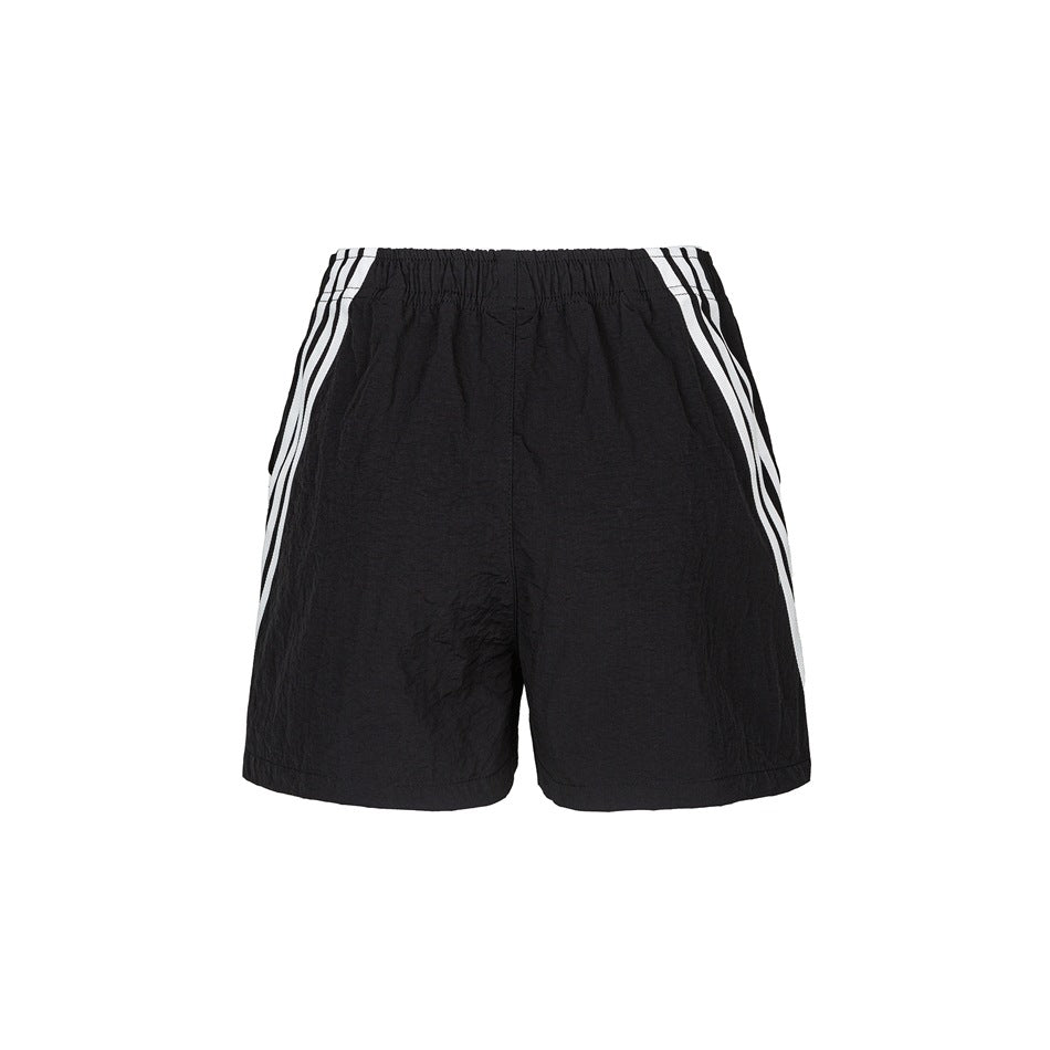 Back view of black shorts with an elastic waistband and three white stripes along each side.