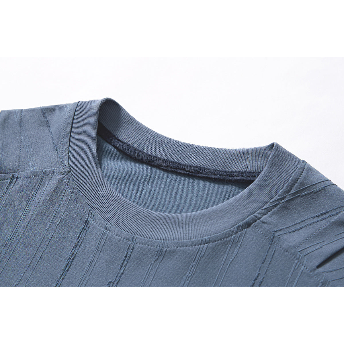 Close-up of a blue crew-neck T-shirt showing its ribbed collar and textured vertical stripe pattern.