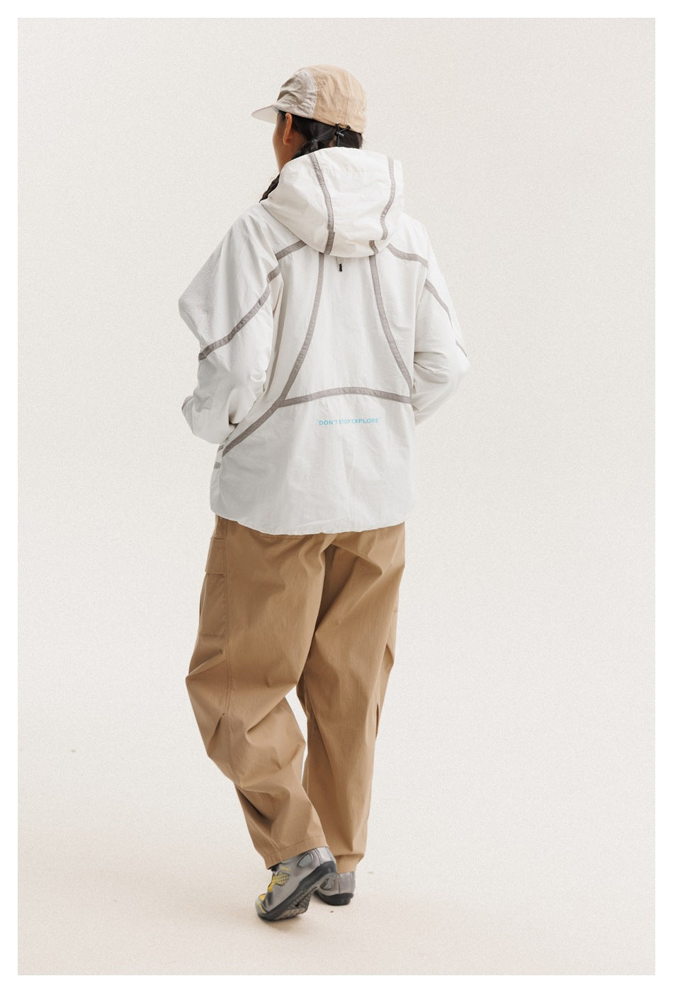 Rear view of a model wearing a white hooded jacket with gray piping and small text near the hem.