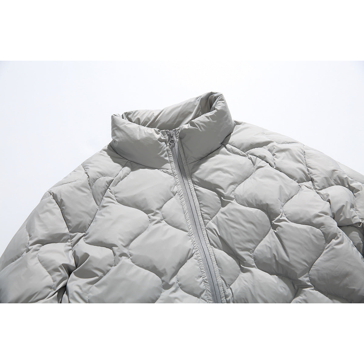 Close-up of a light gray quilted jacket with a high collar and front zipper.