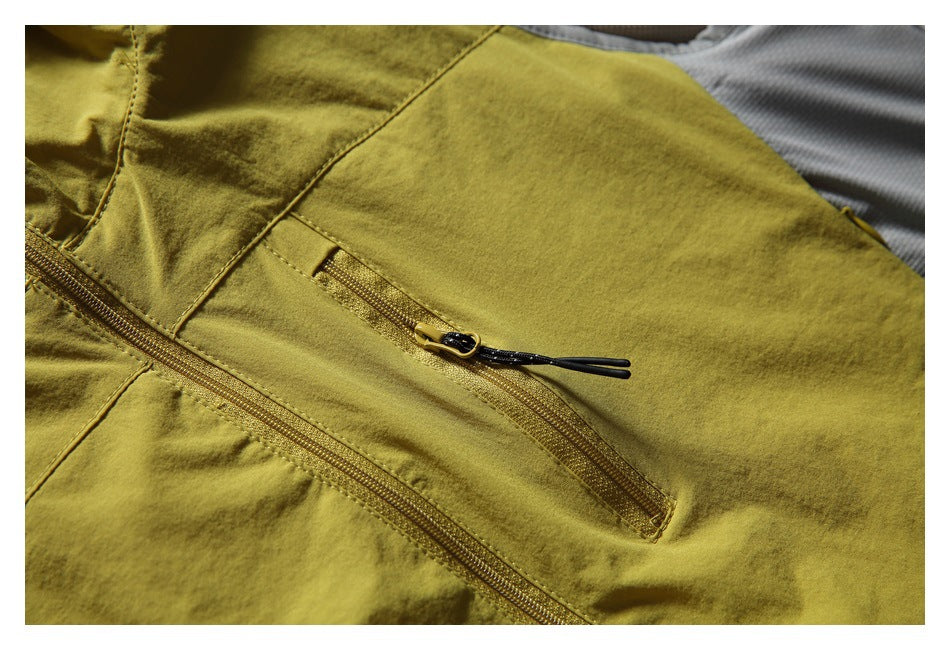 Close-up of the mustard vest's front zip pocket and main zipper, with black zipper pulls.