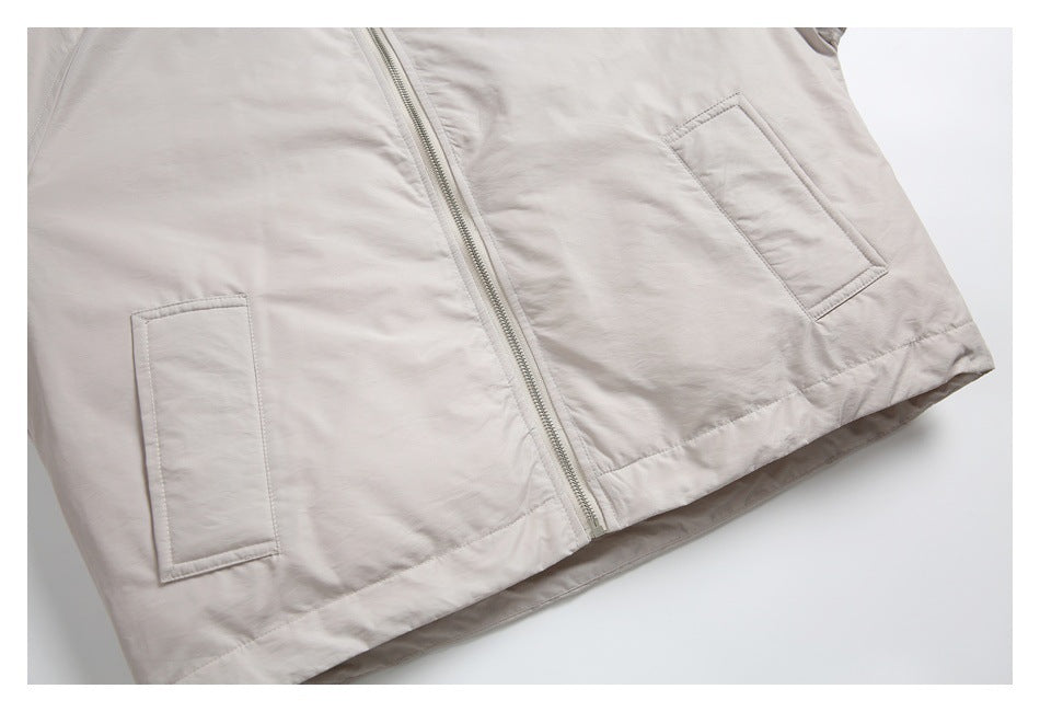 Close-up of the light beige jacket's front zipper, lower hem, and two rectangular pockets.