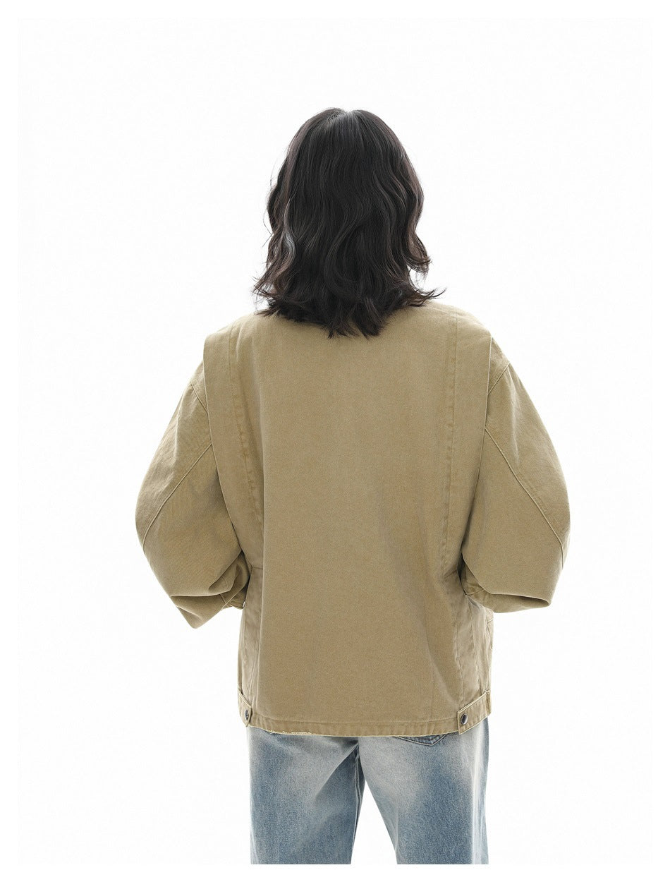 Rear view of a person wearing a tan jacket with oversized sleeves and adjustable hem tabs, paired with light blue jeans.