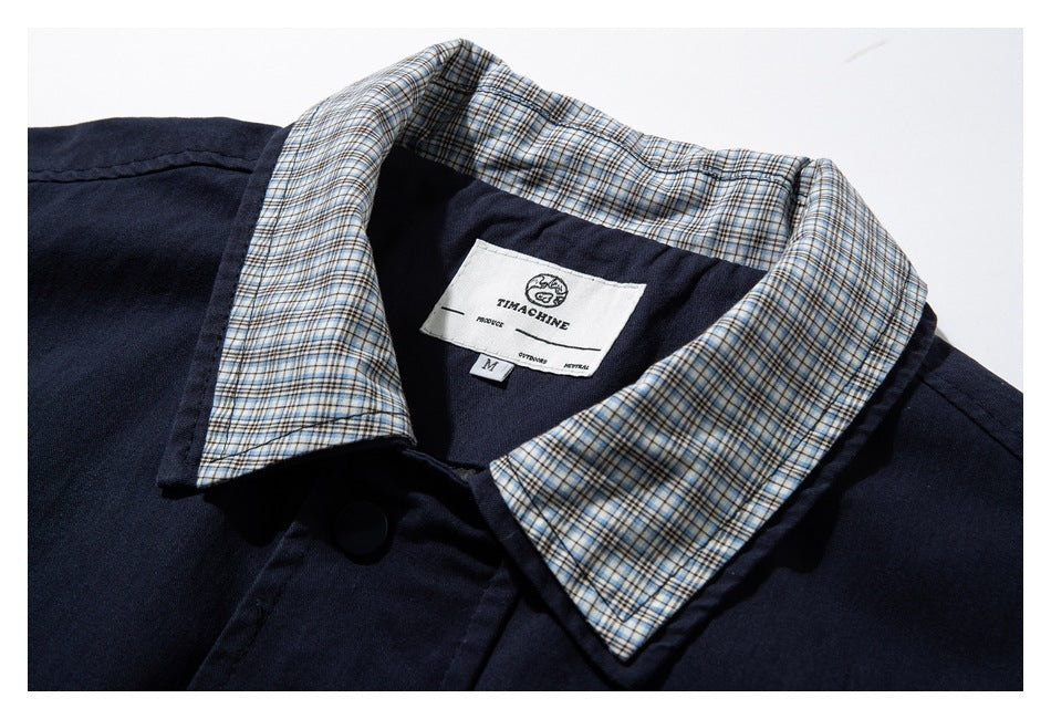 Navy jacket collar with beige-and-blue plaid lining and a sewn-in neck label, shown within a white border.