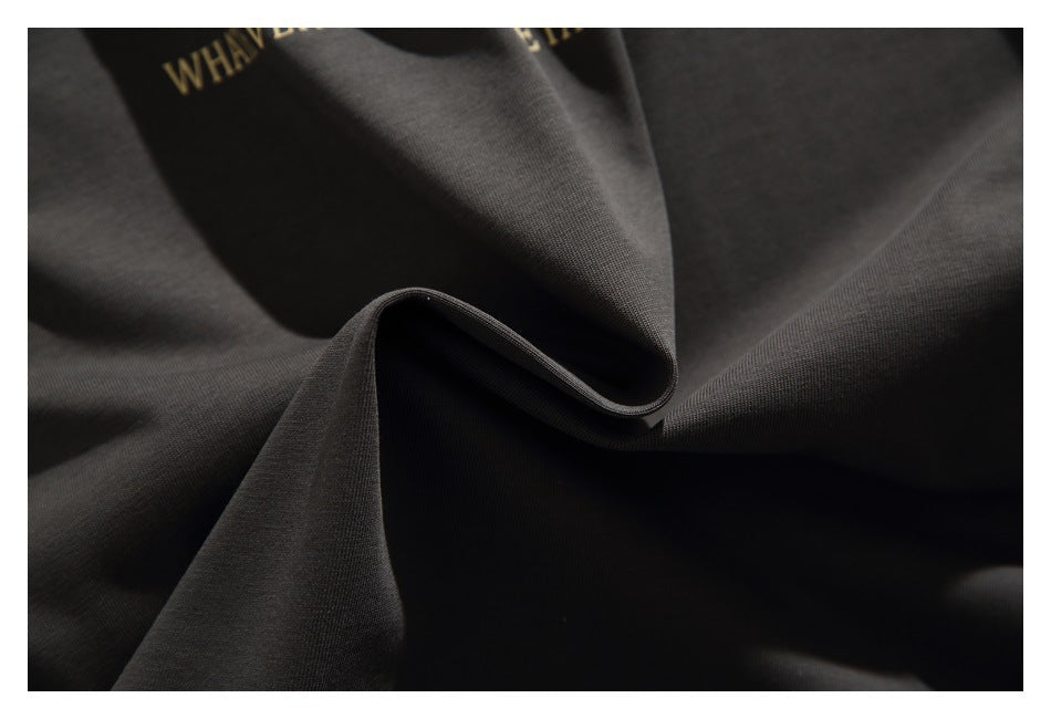 Close-up of charcoal fabric gathered into folds, with a small portion of gold print near the top.