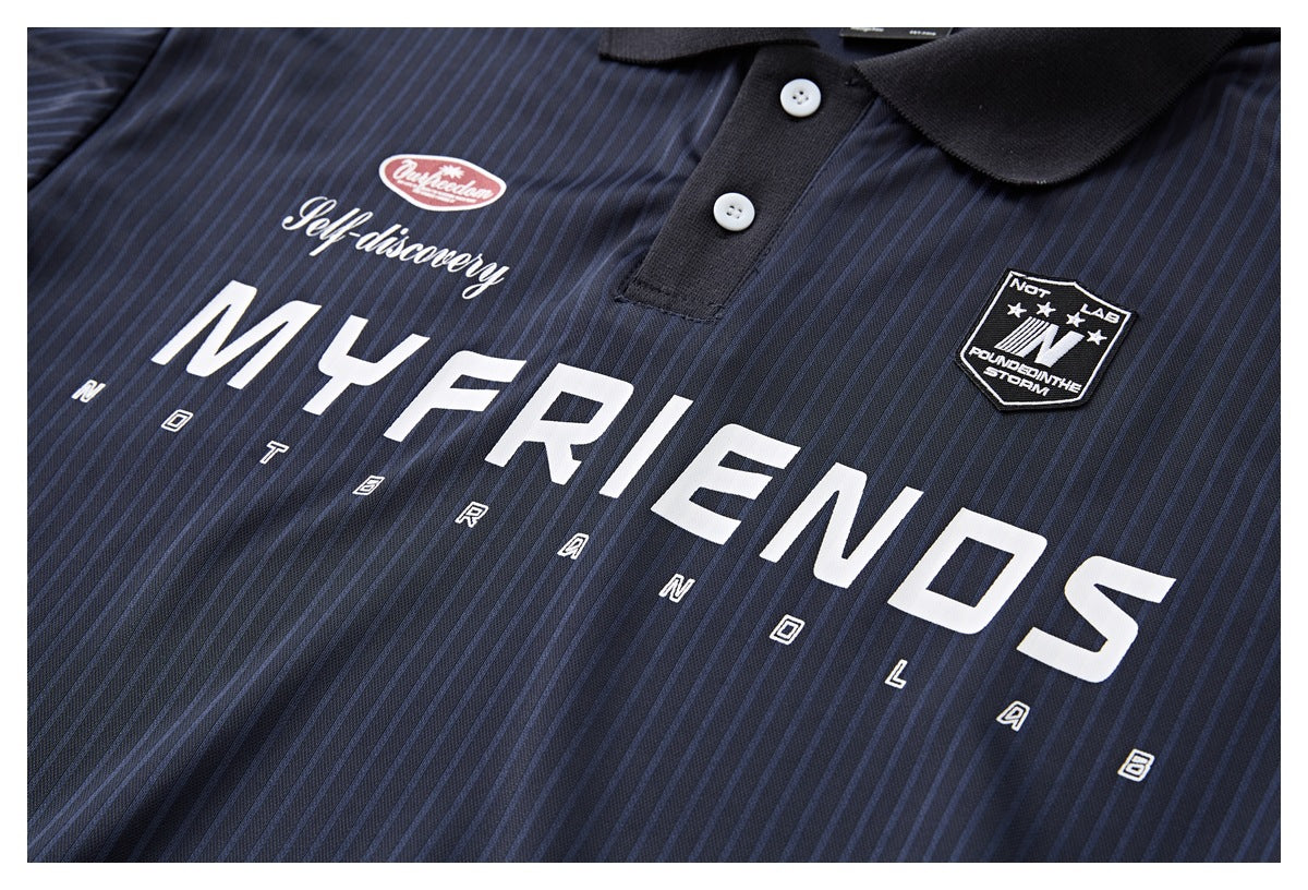Close-up of the navy pinstriped polo’s chest, with bold white lettering, smaller text, and a shield patch.