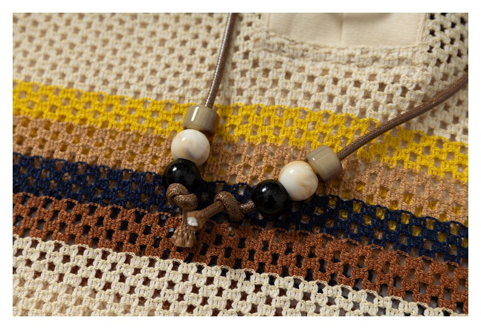 Close-up of a striped open-knit garment with a brown cord and cream, black, and taupe beads.
