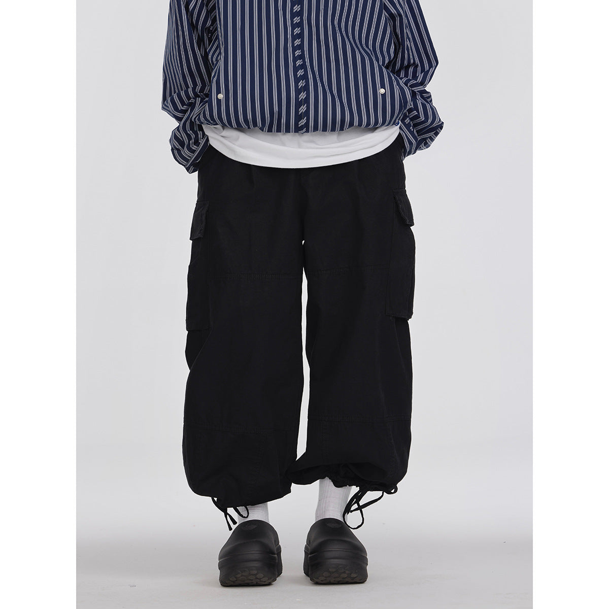 Cropped model wearing black wide-leg cargo pants with large side pockets and drawstring ankle cuffs, front view.