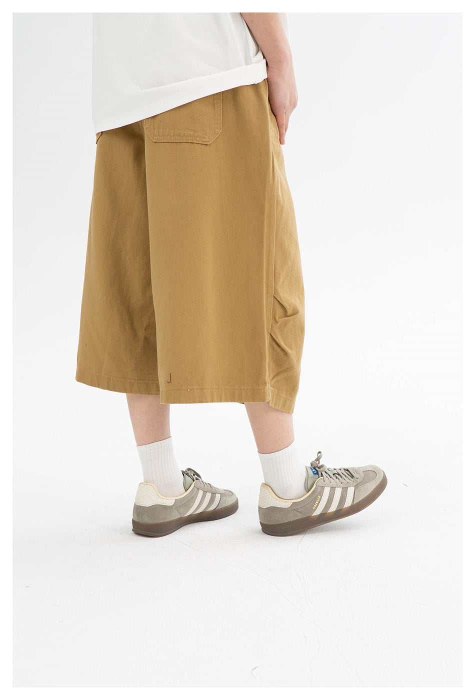 Rear view of tan wide-leg shorts worn with a white top, showing a single back pocket.