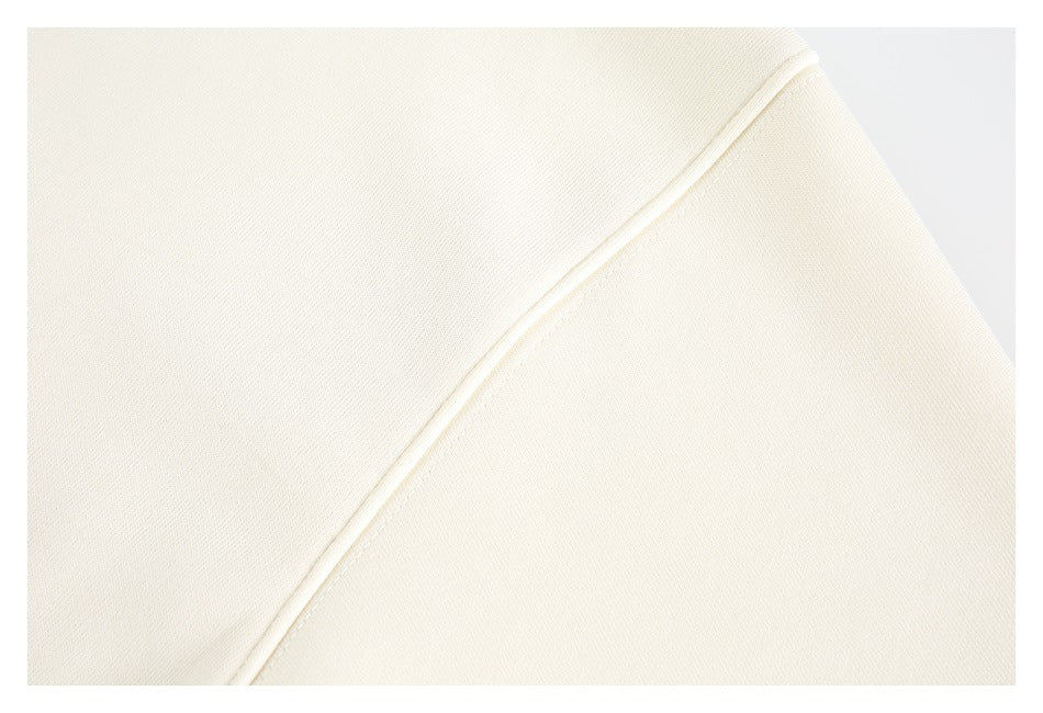 Close-up of a stitched seam across smooth cream sweatshirt fabric.