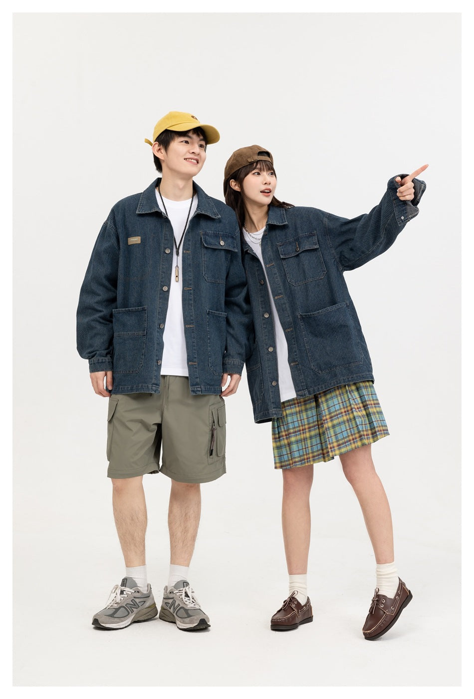Two models wear dark blue denim chore jackets with multiple pockets; one wears cargo shorts and the other a plaid skirt.