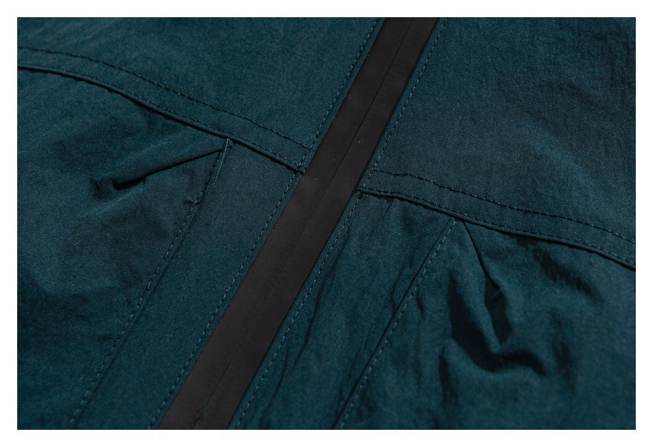 Close-up of dark teal garment panels, stitching, and a vertical black trim strip.