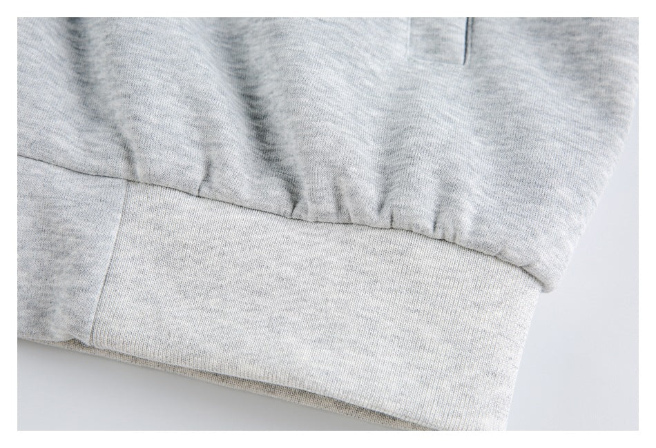 Close-up of the gathered lower hem and ribbed band on a light gray hoodie.