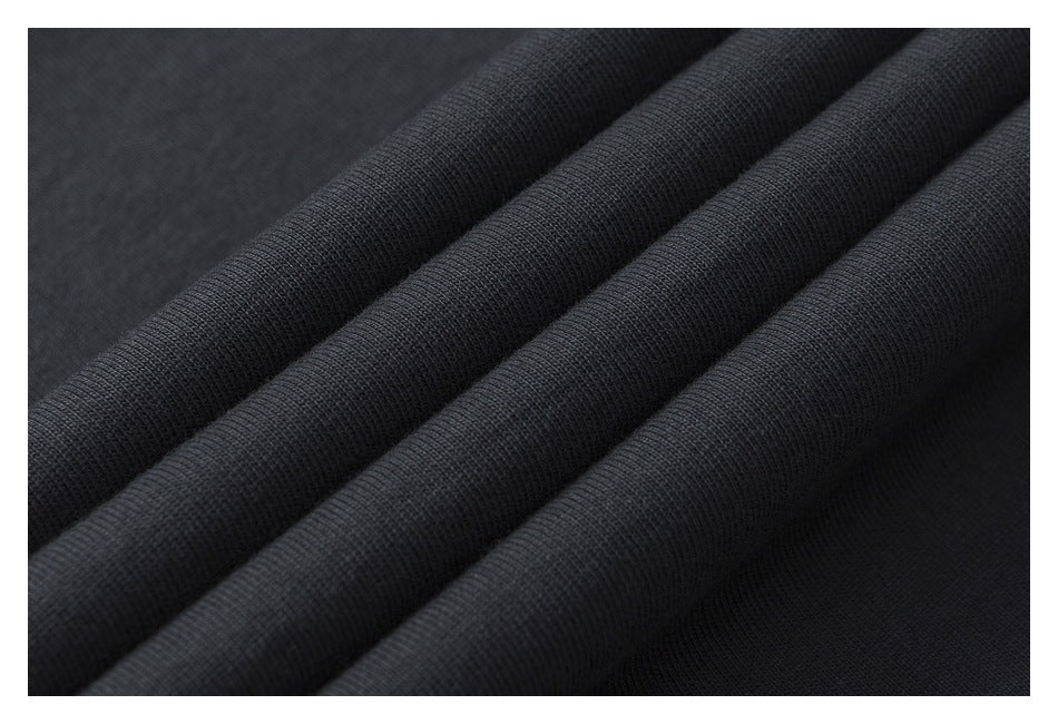 Close-up of dark charcoal fabric arranged in soft folds, showing its surface texture.