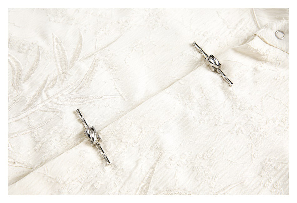 Close-up of cream textured fabric with two silver decorative clasp fasteners.