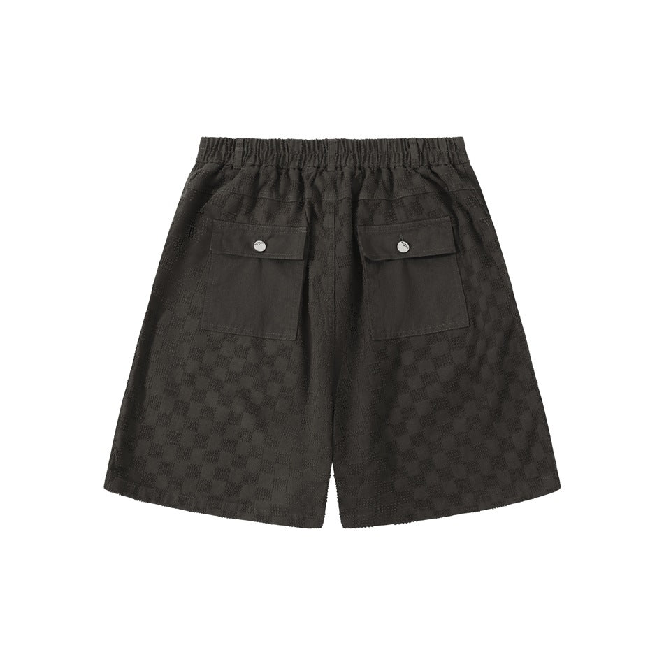 Back view of black checker-pattern shorts with an elastic waistband and two flap pockets.