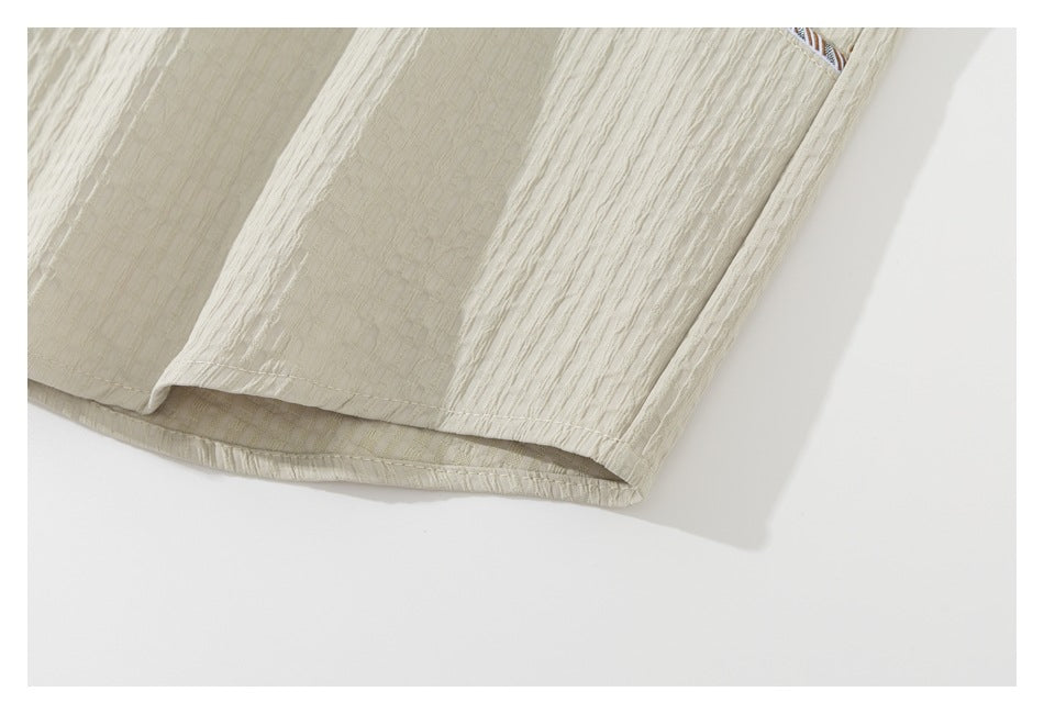Close-up of the curved hem and side seam of a cream textured shirt.