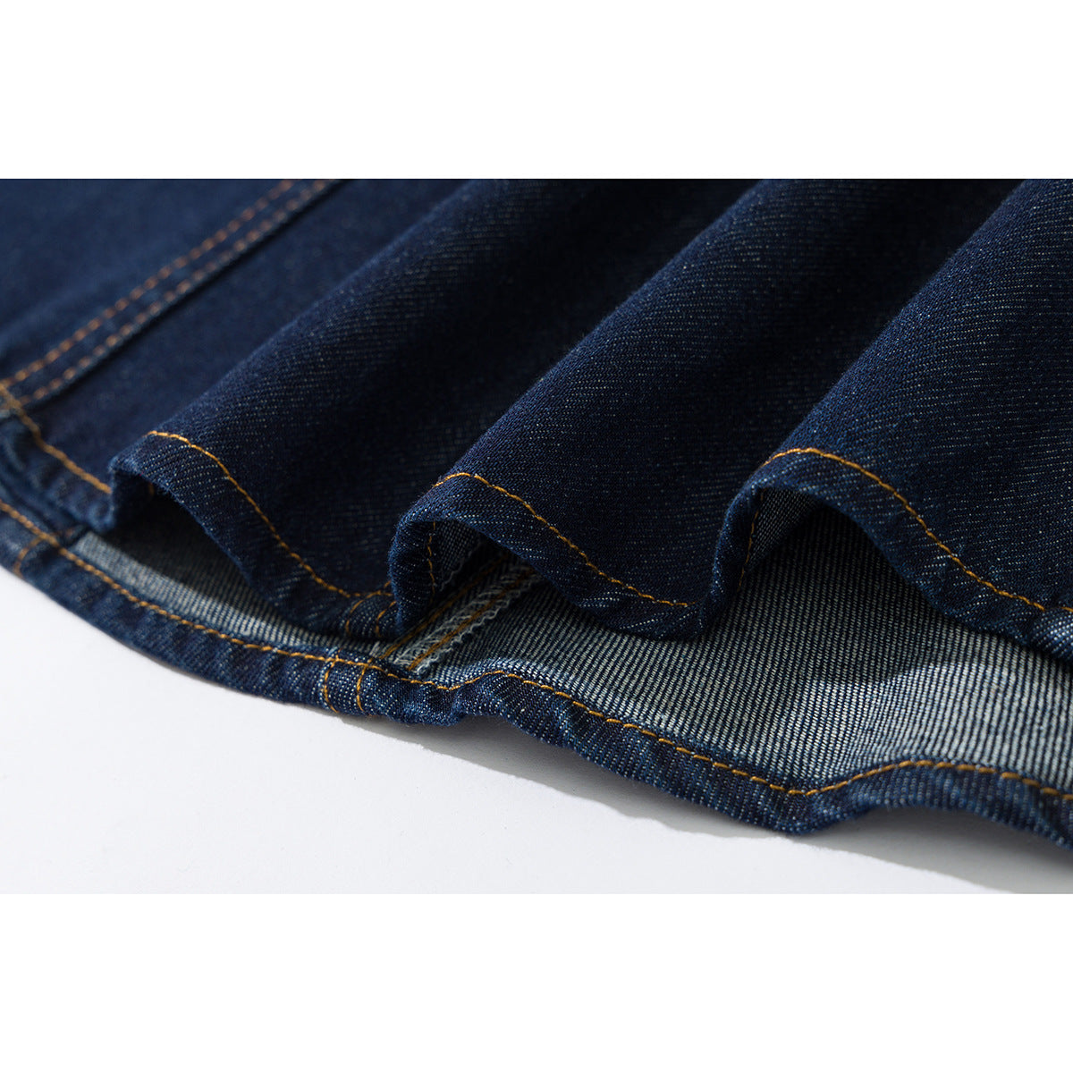 Close-up of the dark indigo denim shirt hem, showing the folded edge and contrast stitching.