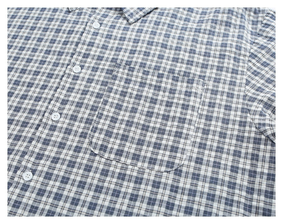 Close-up of the blue-gray plaid shirt front, with white buttons and a single chest pocket.
