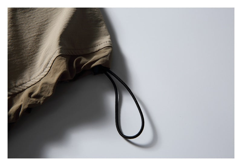 Close-up of a taupe garment hem with a black adjustable drawcord loop.