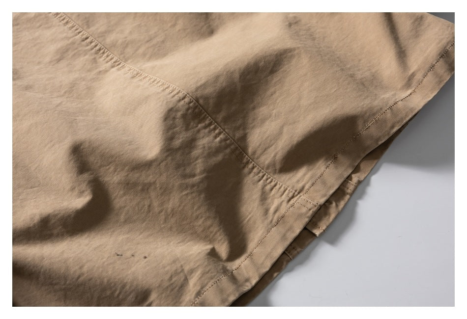 Close-up of tan garment fabric showing a curved stitched seam and finished edge.