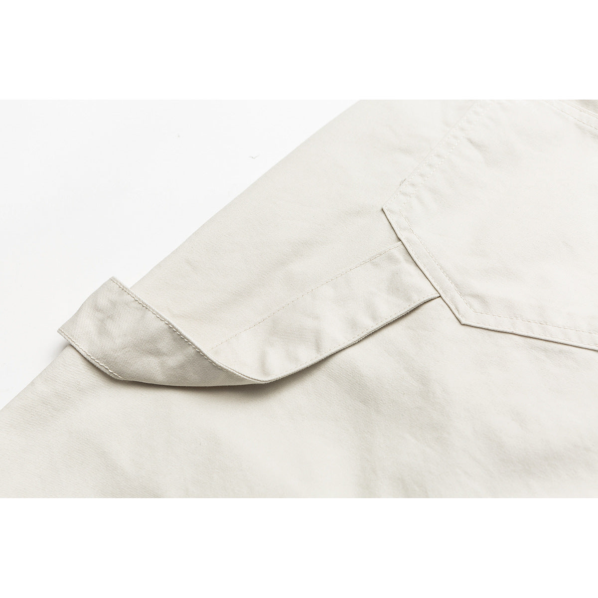 Close-up of a cream shorts leg with a large flap cargo pocket and stitched seams.