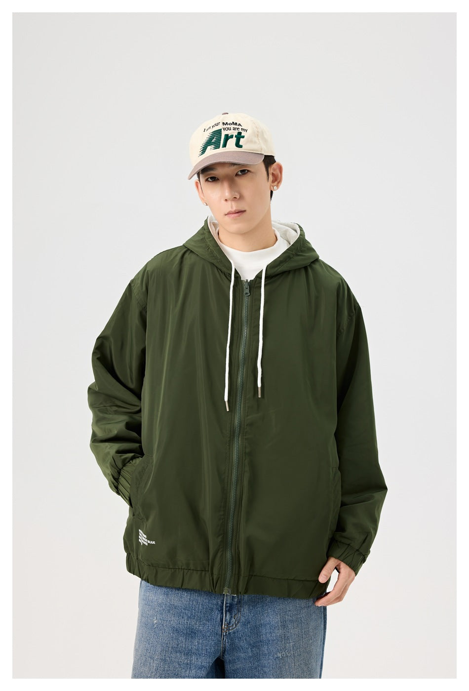 Front view of a model wearing a dark olive green hooded zip jacket with white drawstrings.