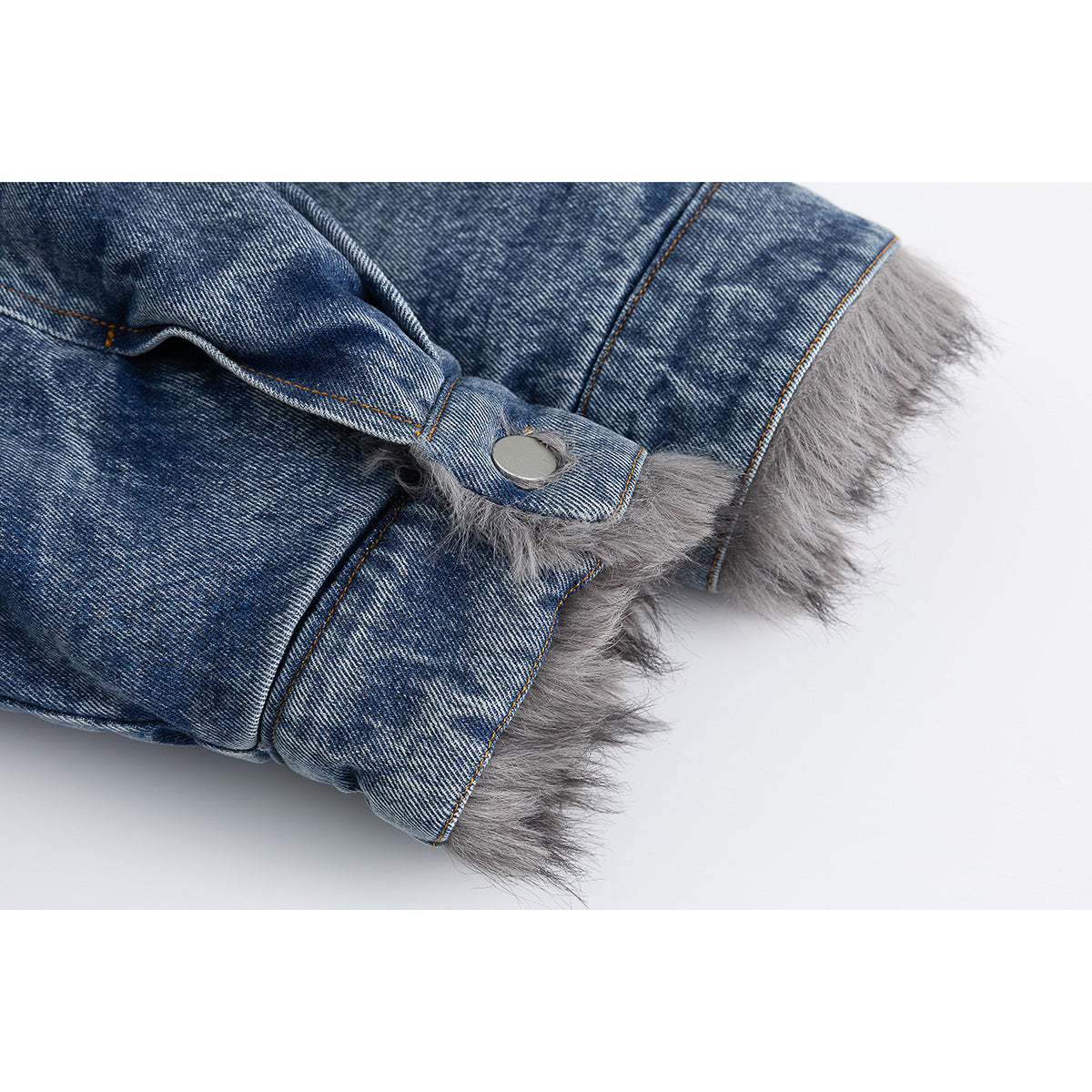 Close-up of a blue denim jacket cuff with gray faux-fur trim and a silver snap button.