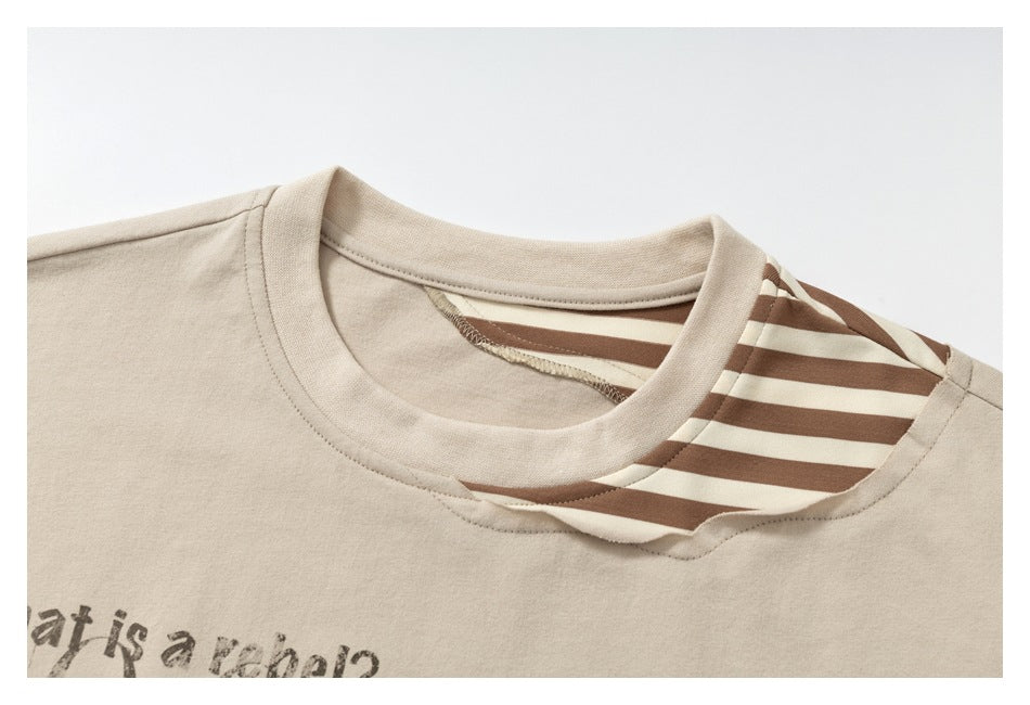 Close-up of the beige T-shirt's crew neck and brown-and-cream striped shoulder panel.