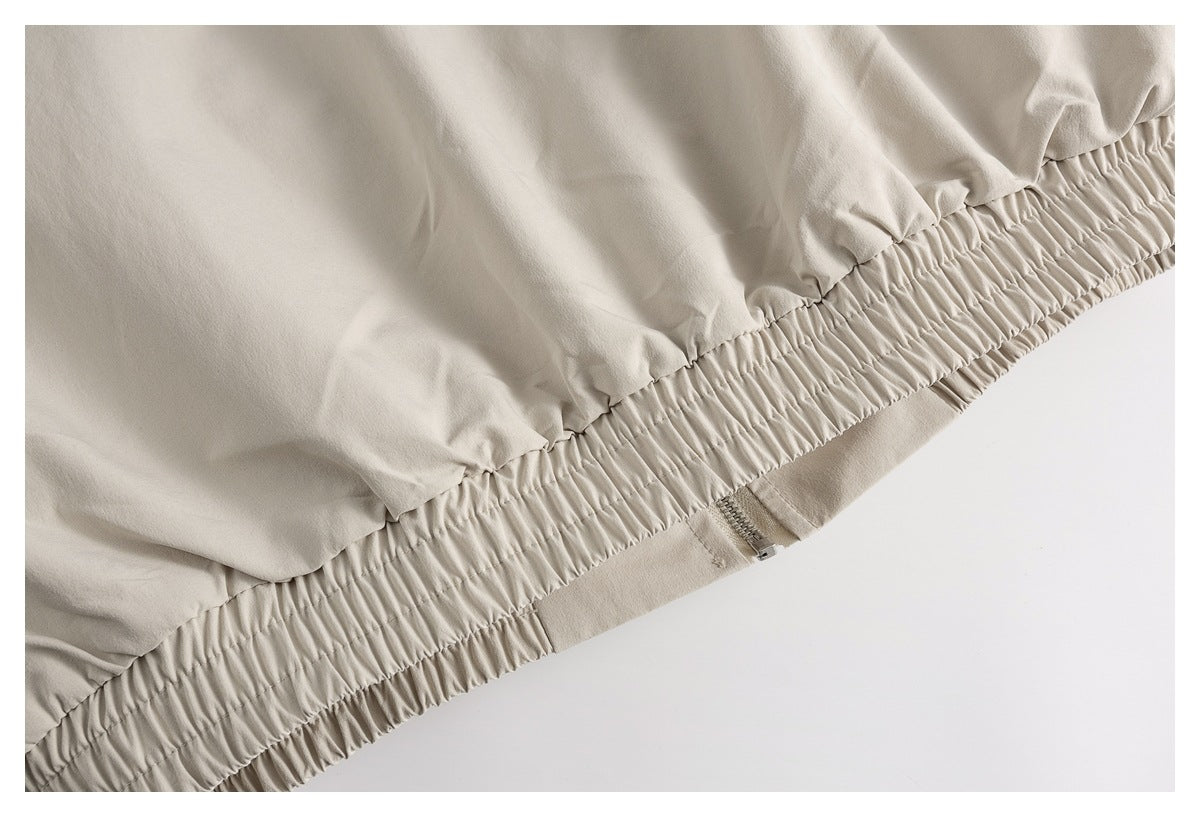 Close-up of a gathered elastic hem and zipper on a light beige garment.