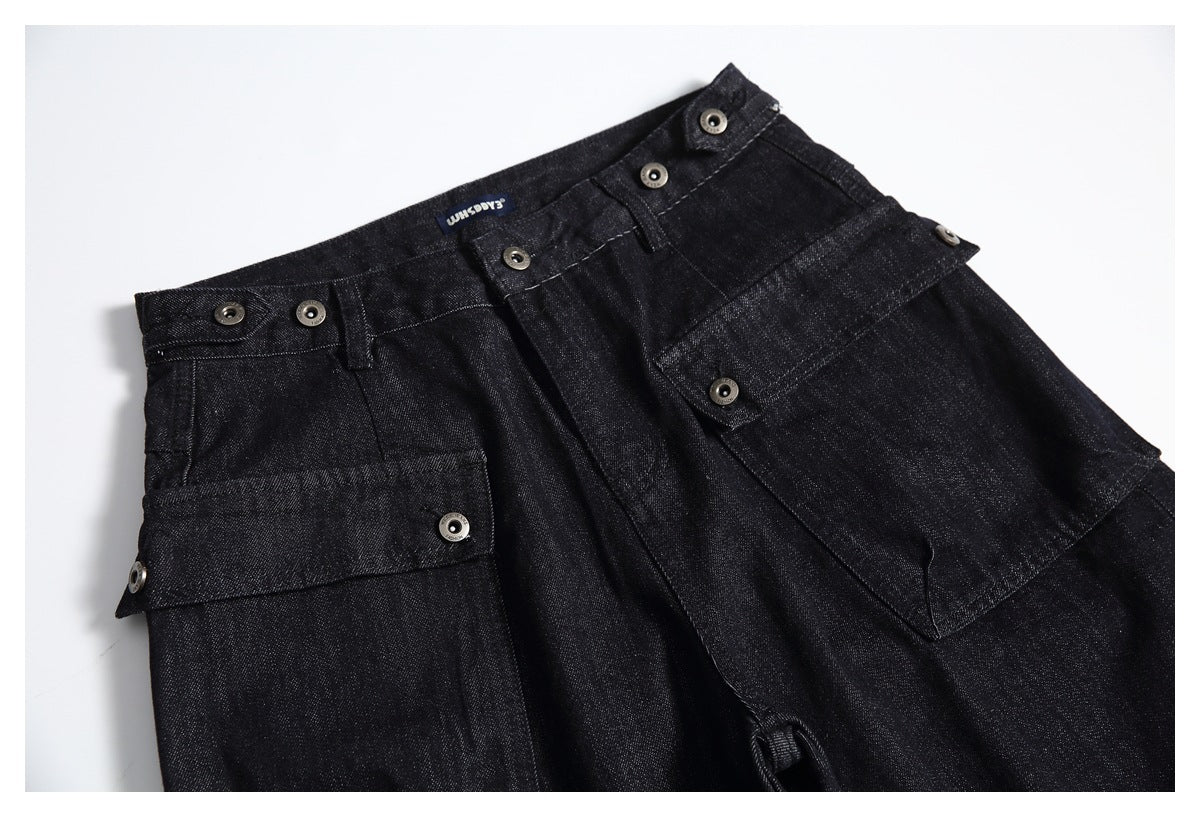 Angled view of the upper front of black denim trousers with buttoned waistband tabs and large utility pockets.