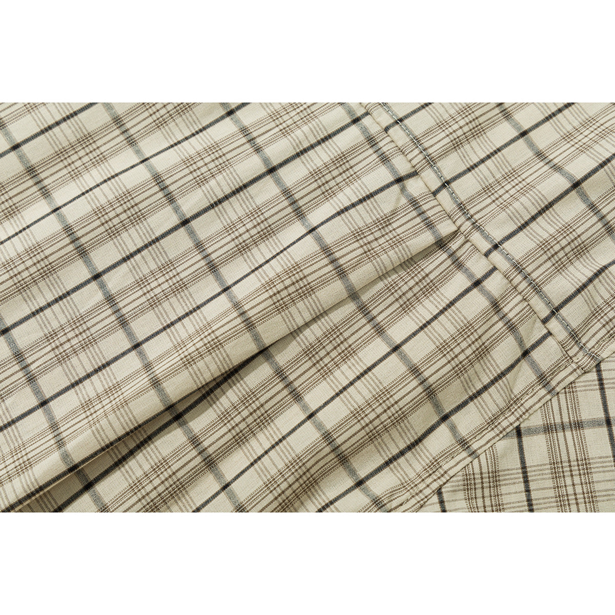 Close-up of beige plaid shirt fabric and a stitched seam.