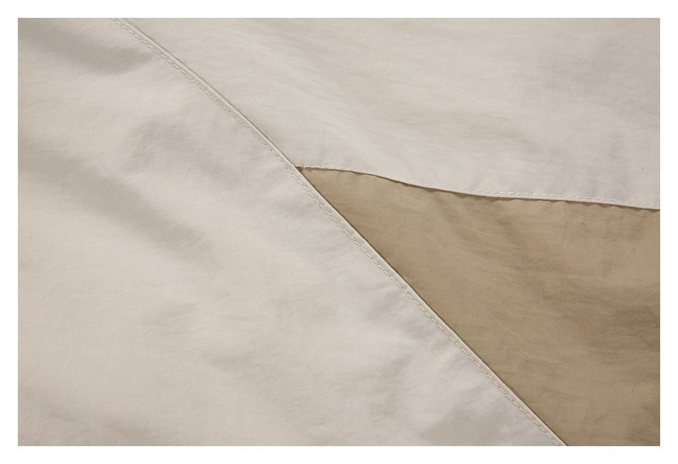 Close-up of cream and tan color-blocked jacket panels with visible stitching.