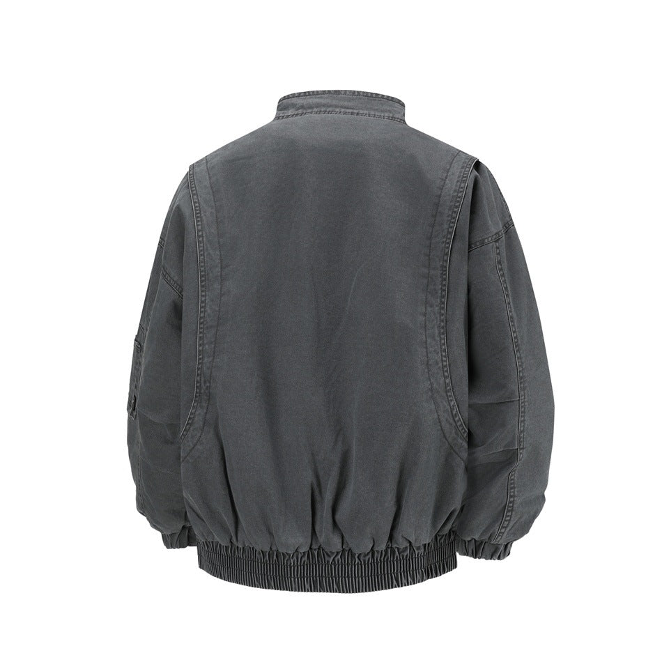 Back view of a dark gray washed bomber-style jacket with curved seams, stand collar and elastic ribbed hem