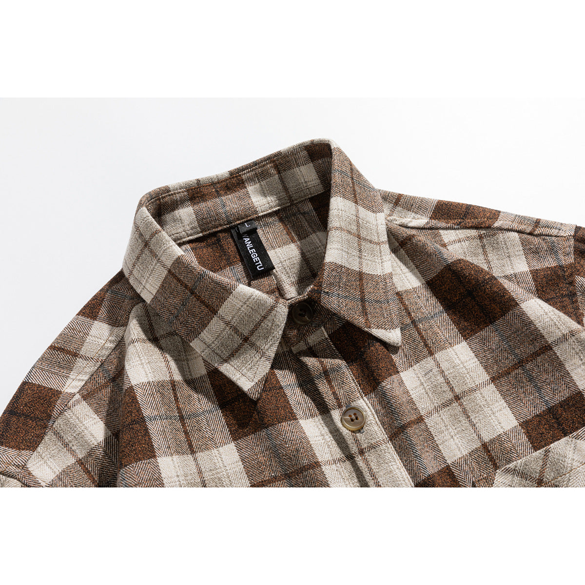 Close-up of a brown, taupe, and cream plaid shirt collar, buttons, and a black neck label.