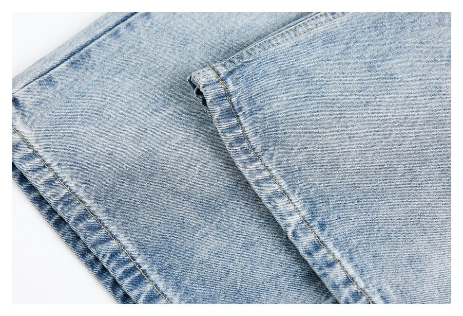 Close-up of light blue denim trouser legs and stitched hems.