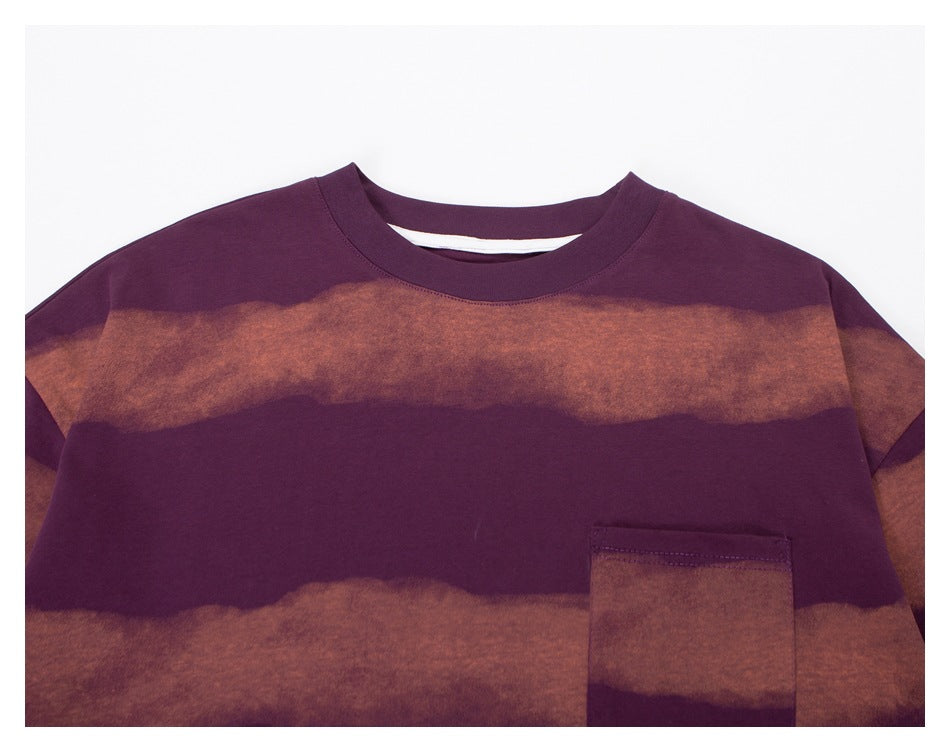 Close-up of a purple sweatshirt showing its crew neckline, broad muted rose stripes, and front chest pocket.