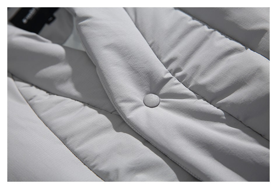 Close-up of a light gray padded jacket showing a covered snap button and quilted panels.