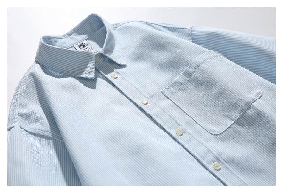 Light blue and white striped button-up shirt laid flat at an angle, showing its collar, buttons, and chest pocket.