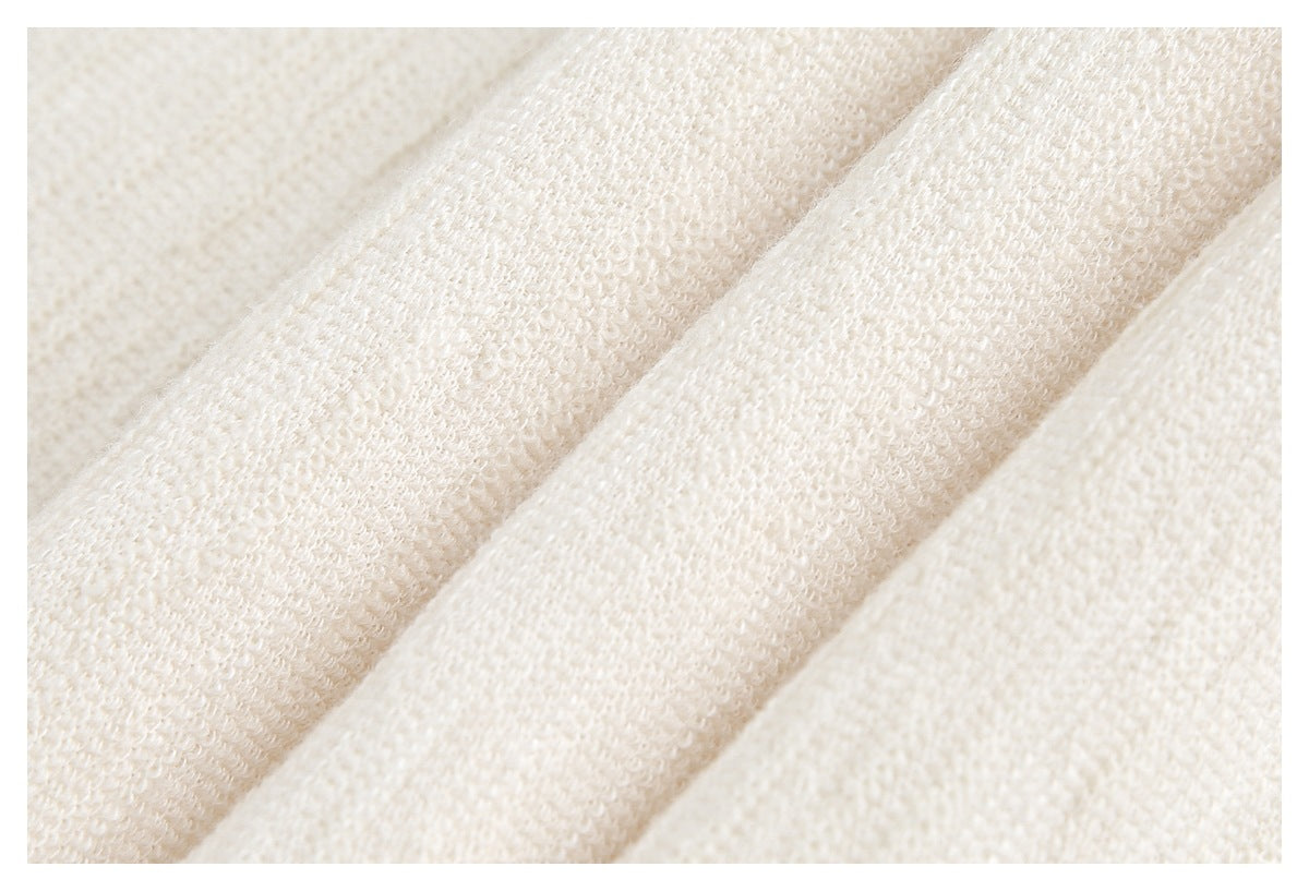 Macro view of the ivory garment's looped knit texture and folded fabric edge.