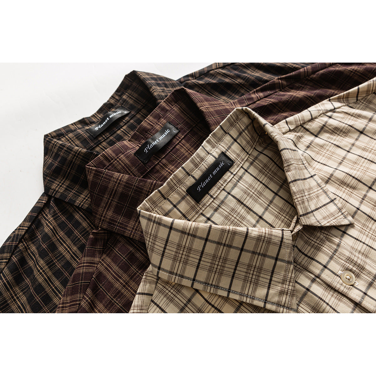 Close-up of three short-sleeve plaid shirts in beige, brown, and dark brown, showing their collars and sewn labels.