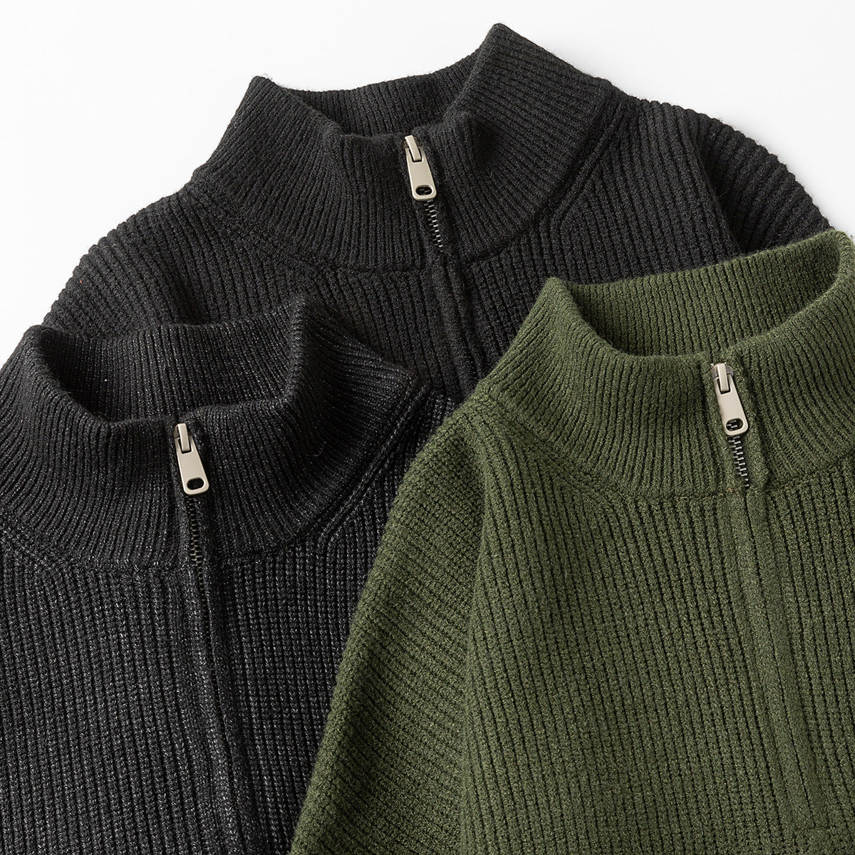 Close-up of black and olive ribbed quarter-zip sweaters, showing their collars, zippers and knit texture.