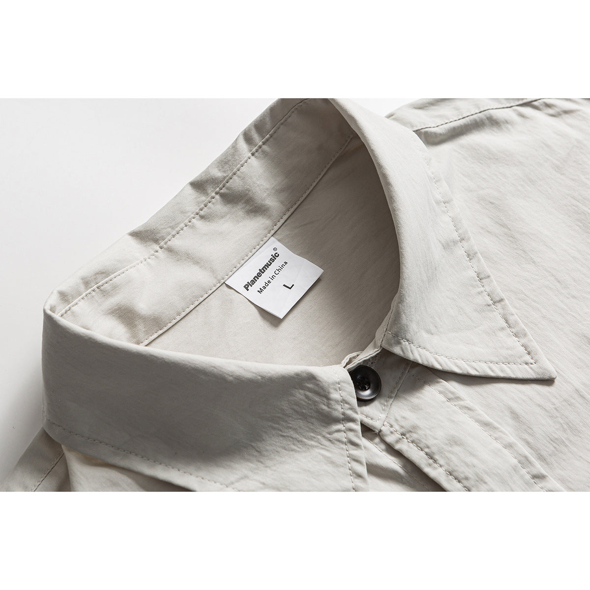 Close-up of a light gray button-up shirt collar, dark button, and inner brand and size label.