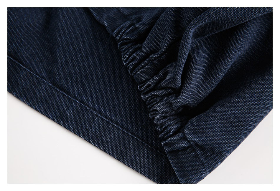 Close-up of gathered stitching and a seam on dark navy textured fabric.