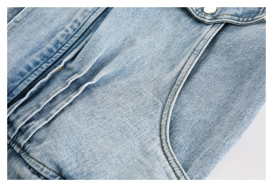 Close-up of a curved pocket opening and stitched seam on faded blue denim.