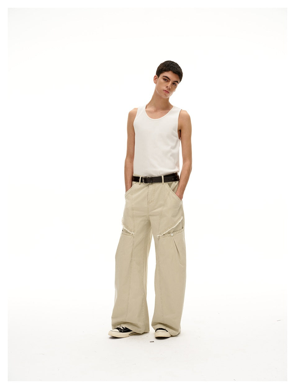 Model in light khaki wide-leg pants with hands in pockets, showing snap thigh pocket and frayed slit detail