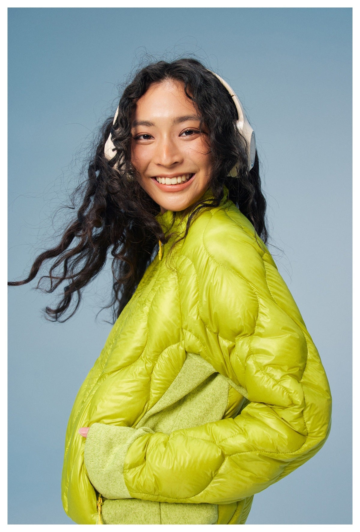 Close view of a model wearing a lime-green quilted jacket with contrasting sleeve panels.