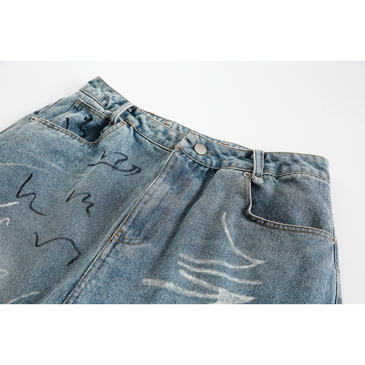 Close-up of the front waistband and pocket area of faded blue denim shorts with black and white decorative markings.