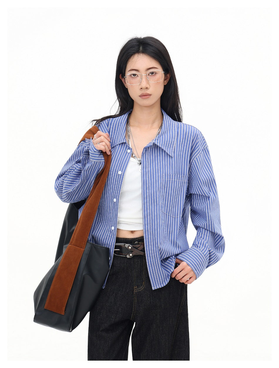 Closer view of a model in an open blue-and-white striped shirt with a pointed collar, buttons, and chest pocket.