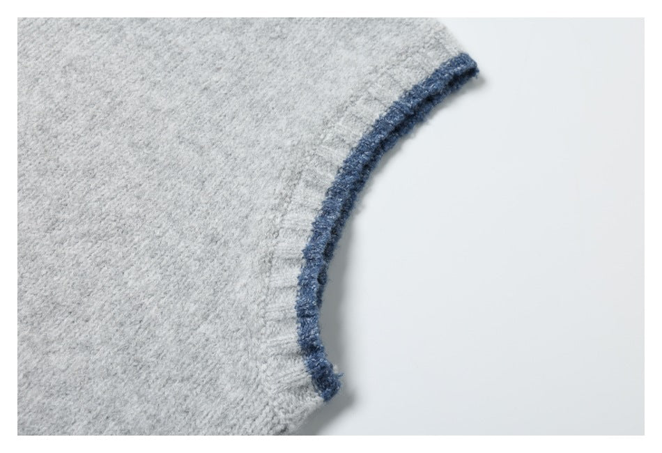 Close-up of the curved, dark blue-trimmed armhole on a light gray knit top.